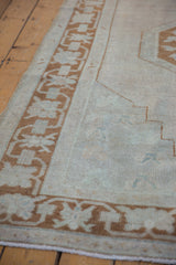 Side border of distressed Oushak rug with pale bronze motifs and softly worn ivory pile.