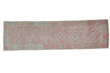 Distressed vintage Oushak runner with muted pink and silver stepped diamond patterns.