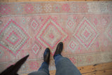 Distressed pink Oushak runner with stepped diamond and pinwheel motifs, showing even wear.