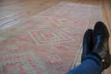 Distressed Oushak runner with faded blush pink and ivory geometric patterns.