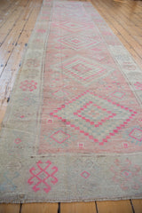 Distressed Oushak rug runner showing pink geometric pinwheel motifs and ivory side selvage.