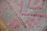 Distressed Oushak rug pile showing even wear, with pink, blush, and silver pinwheel motifs.