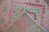 Distressed pink and pale blue geometric pile showing hand-knotted reverse of vintage Oushak.