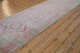 Distressed Oushak runner border, showing faded pink, ivory, and pale blue stepped diamond patterns.