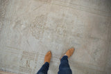 Distressed vintage Oushak rug texture, showing faded floral motifs and soft neutral tones.