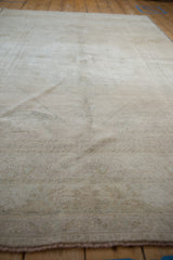 Vintage distressed Oushak rug showing faded floral motifs in ivory and oxidized silver.
