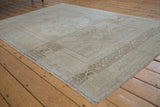 Distressed vintage Oushak rug corner, showing beige border pattern and mostly intact side selvage.