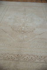 Angled view of the distressed beige and ivory Oushak rug's faded floral design.