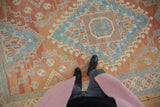 Evenly worn low pile texture of a vintage Oushak carpet with a blue and red medallion.