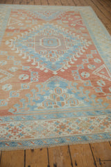 Angled view of a distressed Oushak carpet with a soft red and blue geometric medallion.