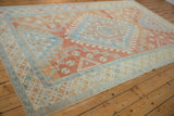 Angled view of a vintage distressed Oushak carpet, showing the geometric medallion design in sky blue and cinnabar red.