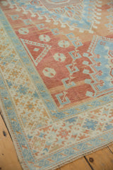 Angled view of the Oushak carpet's corner, showing the time-softened texture and geometric border.