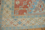 Evenly worn pile on an Oushak corner, showing sky blue and cinnabar red geometric motifs.