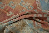 Folded view of the distressed Oushak carpet showing its soft, hand-knotted texture and even wear.