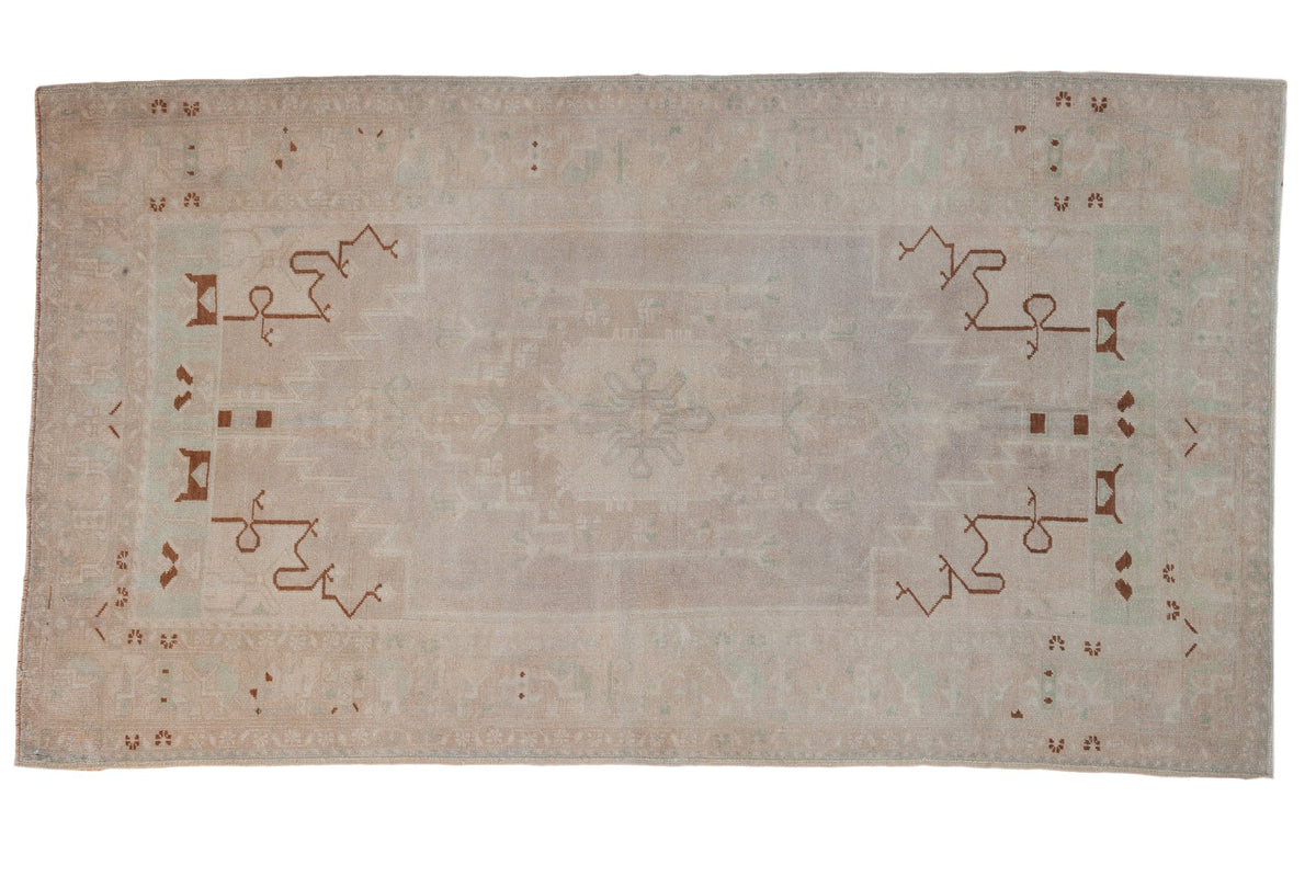 Distressed vintage Oushak rug with a tone-on-tone medallion and bronze vinery on an ivory field.