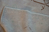 The hand-knotted foundation, low pile, and secured side cord selvage of a vintage Oushak rug.