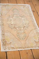 Distressed corner of an Oushak rug, showing intact selvage, beige pile, and mint patterns.