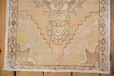 Distressed corner of vintage Oushak rug showcasing wear, secured side cord, and short fringe.