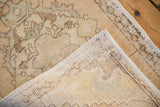 Vintage distressed Oushak rug corner, showing worn beige pile, intact selvage, and woven foundation.