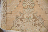 Distressed Oushak rug close-up, worn beige pile, visible foundation, seafoam green, intact selvage.