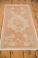 Distressed Oushak mat runner with a muted dusty rose, beige, and wear-softened floral pattern.