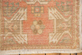 Distressed Oushak rug corner detail with pile wear, fringed edge, and soft neutral tones.