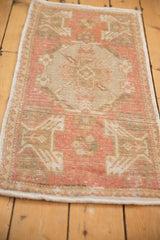 Distressed Oushak rug corner with dusty rose hues, zig-zag border, and intact selvage.