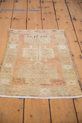 Distressed Oushak rug texture showing faded beige, sand, and blush geometric motifs.