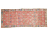 Vintage distressed Oushak runner rug features faded pink allover floral pattern.