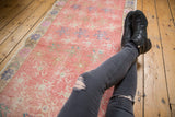 Worn floral motifs and faded pink hues on a distressed vintage Oushak runner.
