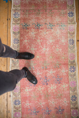 Distressed coral pink field with faded blue and ivory floral patterns on Oushak runner.
