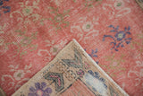 Faded pink Oushak runner pile with wear, folded corner shows hand-knotted foundation.