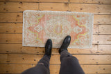 Distressed vintage Oushak mat, with low pile, coral peach, ivory, and saffron yellow patterns.