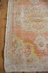 Distressed vintage Oushak rug's intact side selvage and worn coral peach, ivory pile.