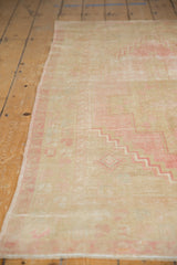Side selvage of vintage distressed Oushak rug, with soft pink stepped pattern and worn pile.