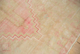 Distressed texture of vintage Oushak rug with soft pink geometric zigzag design.