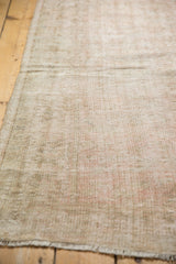 Distressed texture of vintage Oushak rug, showing wear, faded pink, beige, and secured side selvage.