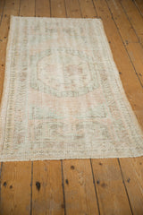 Distressed pile texture on a vintage Oushak runner with faded rose and blue tones.