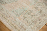 Distressed Oushak rug corner, showing knot heads, visible foundation, and pale rose, ivory.