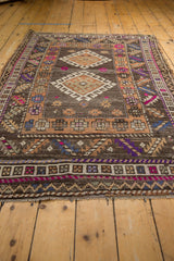 Distressed Oushak rug's hook-and-latch, pinwheel florals, fuchsia, indigo, and textured wear.