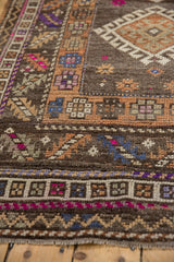 Close-up of vintage Distressed Oushak rug's textured pile and geometric motifs in fuchsia, indigo, beige.