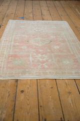 Faded pink, dusty rose, and ivory starburst motifs on distressed Oushak rug.