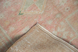 Hand-knotted foundation, secured selvage, and distressed pink and ivory pile of vintage Oushak rug.