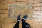 Distressed Oushak rug mat featuring faded rust, green, and gold floral motifs.