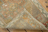 Folded vintage distressed Oushak rug showing low pile, foundation, and woven reverse side.