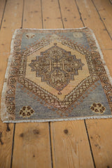 Distressed corner of vintage Oushak mat with slate blue field, palmette border, and fringe.