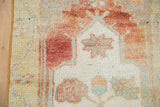 Distressed vintage Oushak rug pile, showing brick red, mint green, and beige pattern detail.