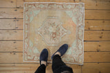 Distressed Oushak rug corner with beige, apricot, seafoam floral medallion and even wear.
