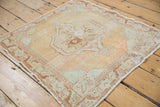 Corner detail of distressed Oushak rug, showing border design and apricot, seafoam tones.