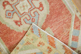 Distressed Oushak rug pile in brick red, ivory, blue, revealing its hand-knotted reverse.